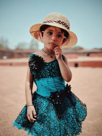 Cute girl wearing hat while standing on field against clear sky