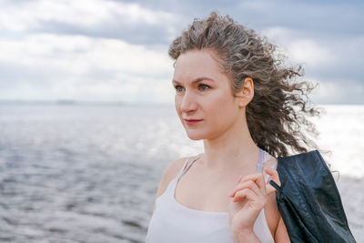 Young stylish woman in light light t-shirt and leather jacket and curly hair