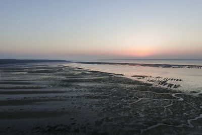 Scenic view of wet beach at sunrise