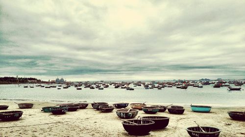 Deck chairs on beach against cloudy sky