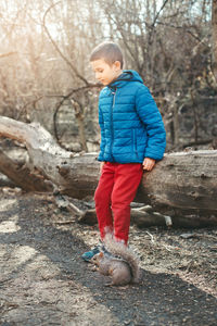 Boy standing by bare tree