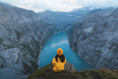 Rear view of man sitting on mountain