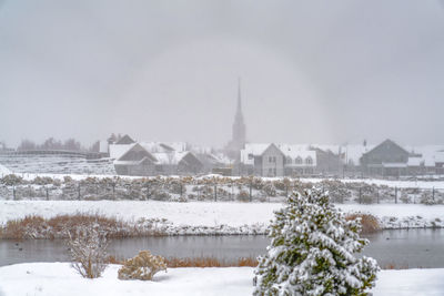 Snow covered by buildings against sky