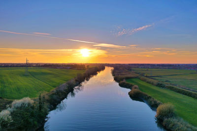 Scenic view of agricultural field against sky during sunset