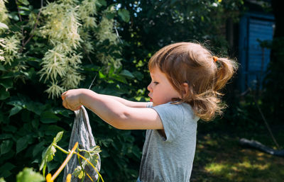 Little preschool girl helps with laundry. child washes clothes in garden