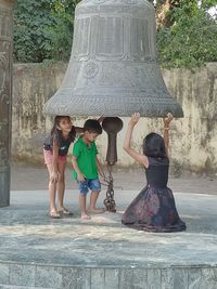 Rear view of people with arms outstretched against trees
