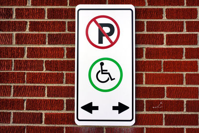 Close-up of wheelchair access sign on brick wall