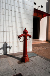 Red fire hydrant on footpath against building