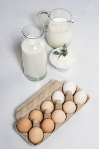 Raw eggs and dairy on rustic white background