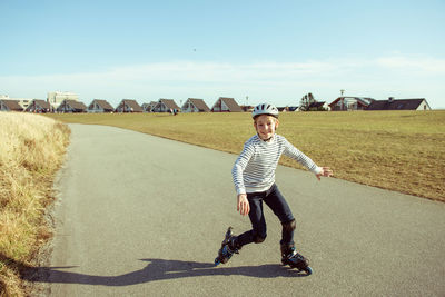 Full length portrait of man skateboarding on road against sky