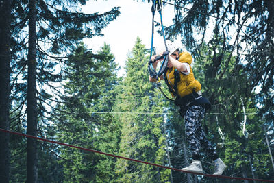 Kid walking on a hanging ropes during canopy tour in adventure park.