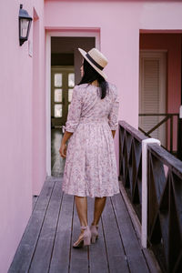 Rear view of woman with umbrella standing against building