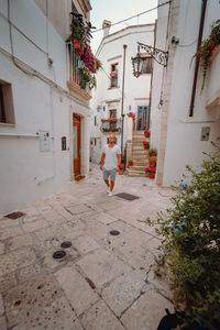 Rear view of woman walking on footpath amidst buildings in city