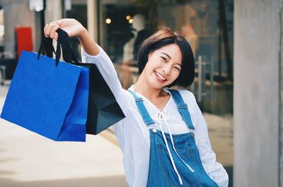 Happy young woman holding umbrella at store