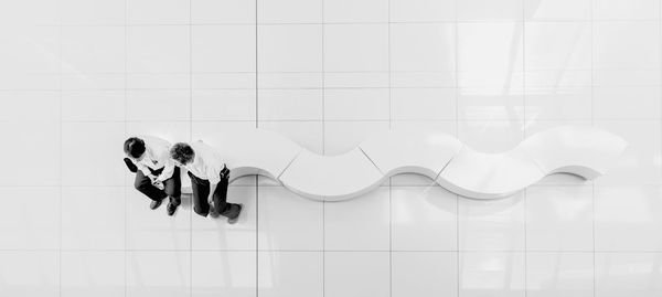 Directly above shot of men sitting on white curve bench