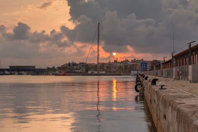 Sailboats moored at harbor against sky during sunset