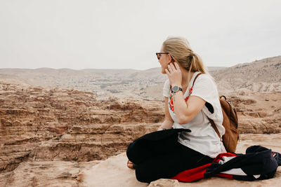 Rear view of woman sitting on landscape against sky