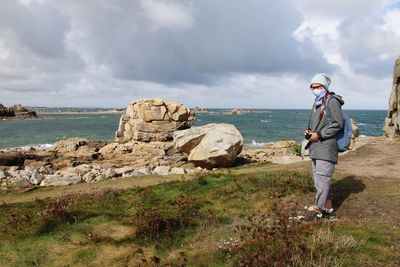 Full length of man standing on rock against sky
