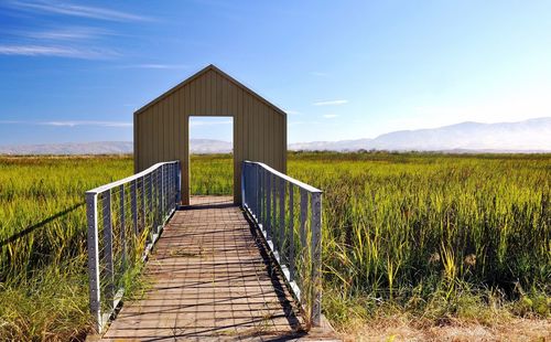 Wooden structure on field against sky