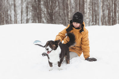 A girl plays with a corgi dog in a winter park