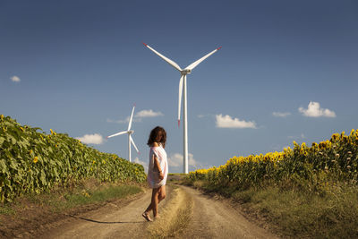 Woman with umbrella on road against sky