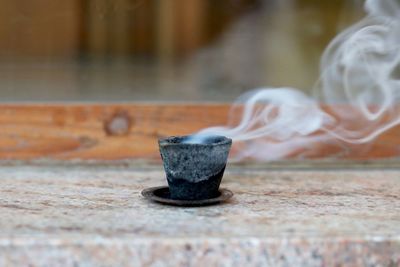 Close-up of smoke emitting from cup on table