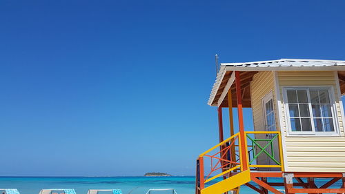 Lifeguard hut on beach against clear blue sky