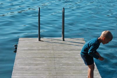 Boy standing on pier over lake