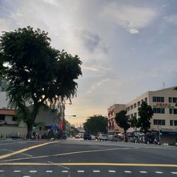 Road by buildings in city against sky