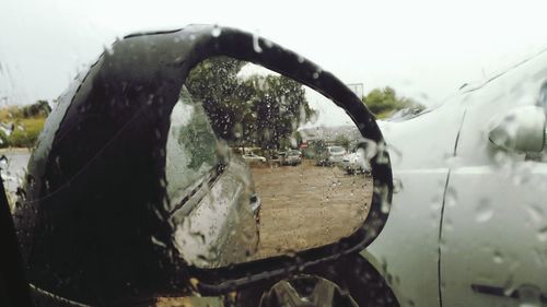 Close-up of car on side-view mirror against sky