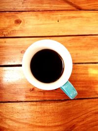 High angle view of black coffee on wooden table