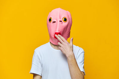 Portrait of woman wearing mask against yellow background