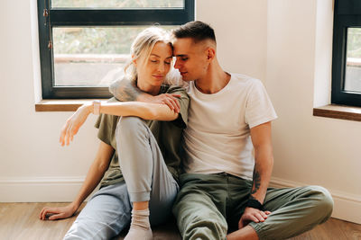 Young loving couple hugging sit on the floor in the living room.