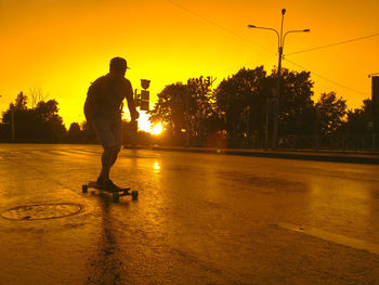 Silhouette of man with arms raised in city at sunset