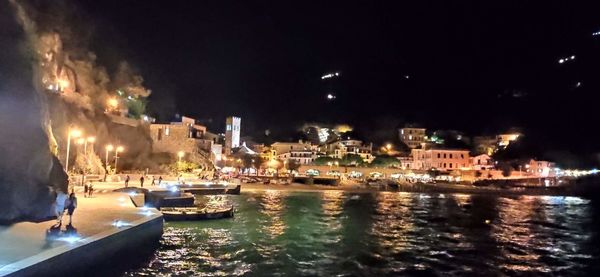 River by illuminated buildings in city at night