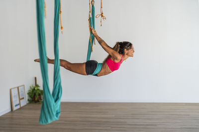 Woman exercising on aerial silk in yoga studio