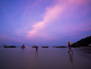 Boats in sea at sunset