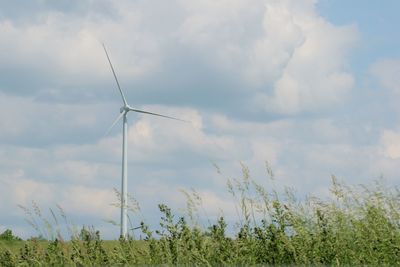 Low angle view of windmill on field against sky