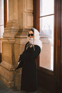 Portrait woman wearing sunglasses standing against door