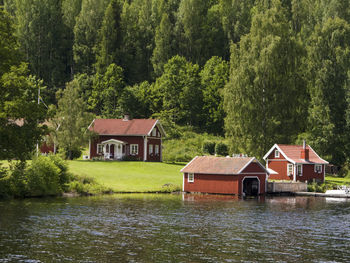 House and trees by lake against building