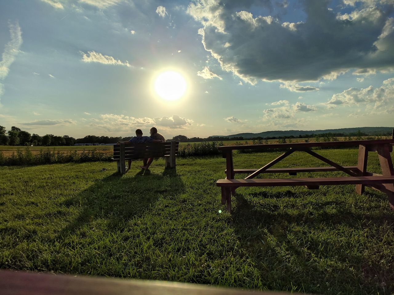 grass, sky, field, leisure activity, landscape, grassy, men, cloud - sky, sunlight, tranquil scene, lifestyles, tranquility, nature, person, scenics, sun, beauty in nature, togetherness