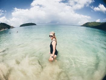 Side view of seductive woman standing in sea against sky