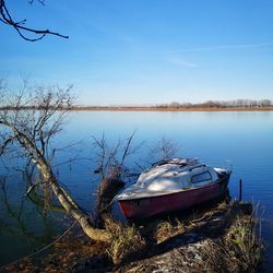 Abandoned boat moored on lake against sky