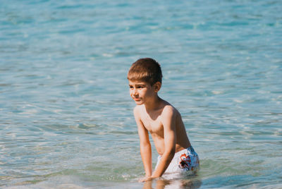 Shirtless boy in sea on sunny day