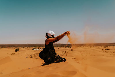 Full length side view of woman walking on sand dune