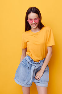 Portrait of smiling girl against yellow background