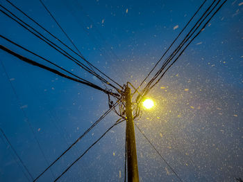 Low angle view of electricity pylon against blue sky