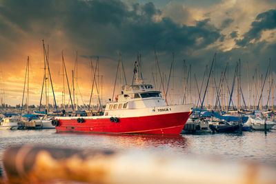 Sailboats moored on sea against sky during sunset