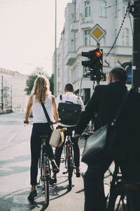 Rear view of people riding bicycle on road