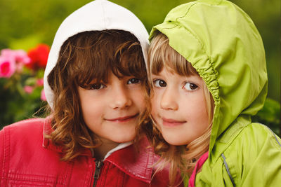 Portrait of smiling friends wearing raincoats at backyard